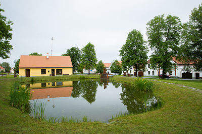 House by lake and buildings against sky