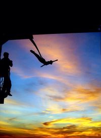 Silhouette of woman against cloudy sky at sunset