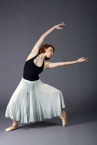 Ballet dancer dancing against gray background