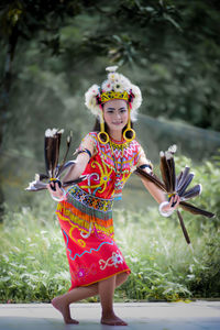 Portrait of young woman with arms raised standing on field