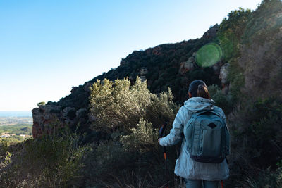 Rear view of man standing on mountain against clear sky
