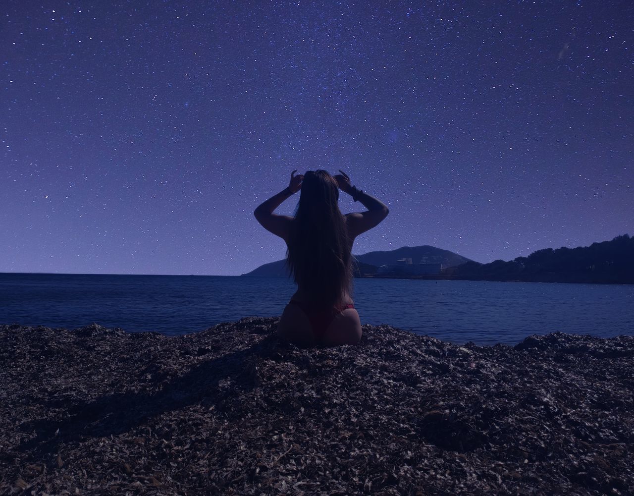 star, sky, one person, night, astronomy, water, sea, space, beach, nature, land, adult, scenics - nature, beauty in nature, galaxy, women, tranquility, horizon, tranquil scene, young adult, leisure activity, darkness, horizon over water, full length, moonlight, standing, lifestyles, rear view, blue, rock, relaxation, idyllic, star field, environment, vacation, outdoors, holiday, trip, solitude, clear sky, spirituality, arts culture and entertainment, infinity