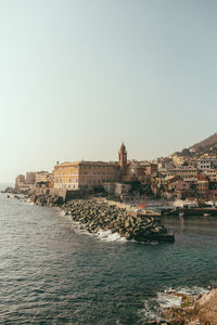 Buildings at waterfront against clear sky