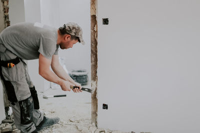 A man working with a crowbar in a doorway.