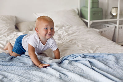 Child in a white t-shirt and shorts sitting on a big bed