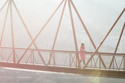 Man standing on railing against sky