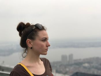 Portrait of young woman looking away against sky