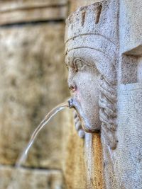 Close-up of old statue against wall