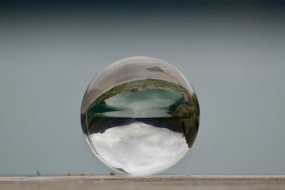 Close-up of crystal ball against sky