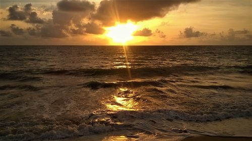 Sun shining through clouds over sea