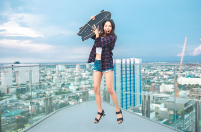 Full length of young woman standing against sky in city
