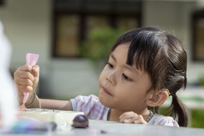 Close-up of cute girl playing with childs play clay at table outdoors