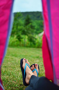 Low section of woman wearing flip-flop lying in tent