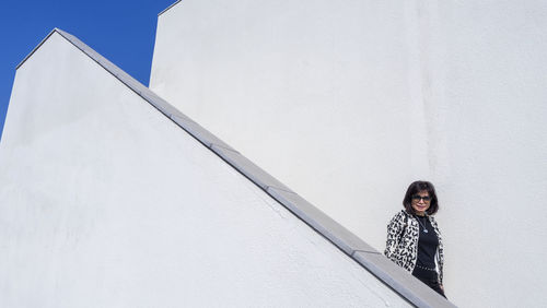 Portrait of woman standing against white wall