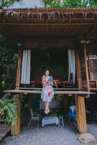 Full length of woman sitting on chair against building