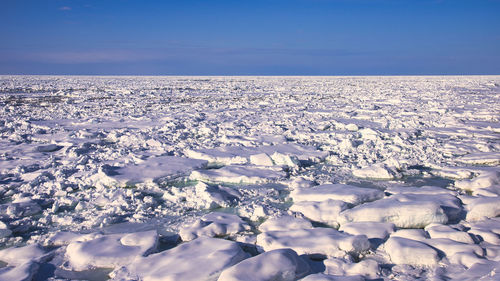 Scenic view of snow covered landscape against blue sky