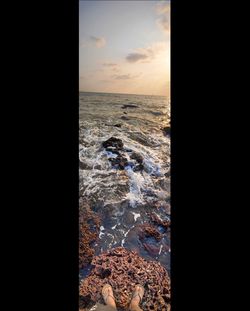 Digital composite image of rocks in sea during sunset