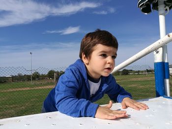 Boy on outdoors play equipment against sky