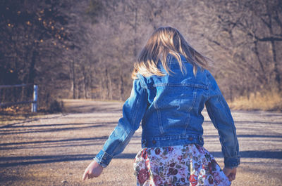 Rear view of woman walking on road