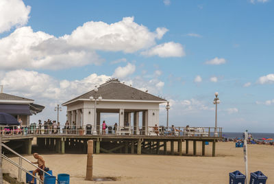 People on beach boardwalk by building against sky