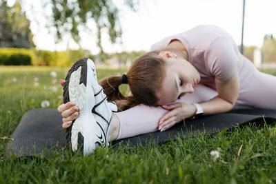 Athletic girl doing a warm-up on a fitness mat in the park
