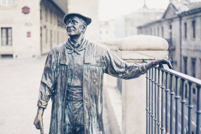 Statue of man standing by railing in city