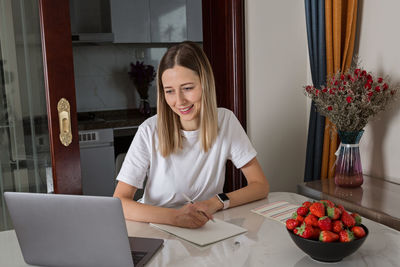 Young woman using phone while sitting on table