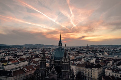 Cityscape against cloudy sky at sunset