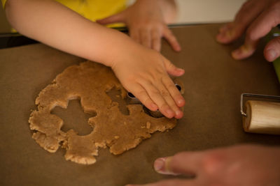 Cropped hands of girl preparing cookie at table
