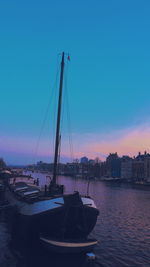 Sailboats moored in sea against sky during sunset