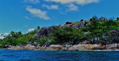 Scenic view of rocks by sea against sky