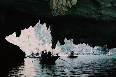 Silhouette people on rock formation in sea