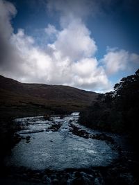Scenic view of river amidst mountains against sky
