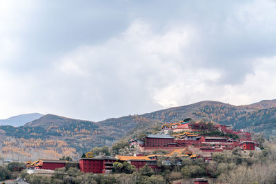 Houses by buildings against sky