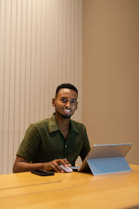 Young man using laptop while sitting on table