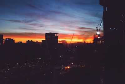 Illuminated cityscape against sky at sunset