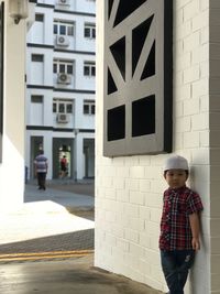 Full length of a boy standing against built structure