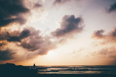 Silhouette man standing on beach against sky during sunset