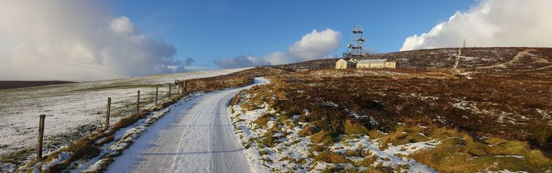 Road amidst snow covered landscape against sky