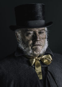 Portrait of tough looking man wearing hat against black background