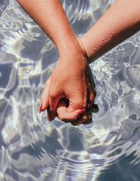 Cropped image of people holding hands in swimming pool