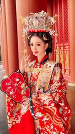 Portrait of smiling young woman standing against wall