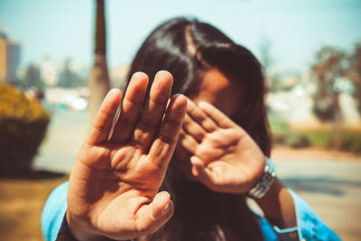 Woman covering face with hands on sunny day