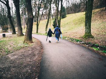 Rear view of people walking on road amidst trees