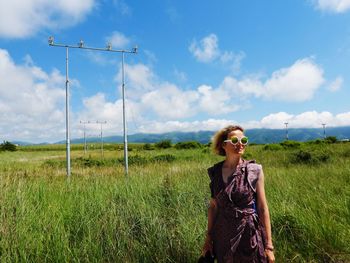 Young woman on field against sky