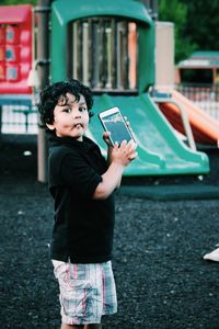 Portrait of boy holding mobile phone at playground