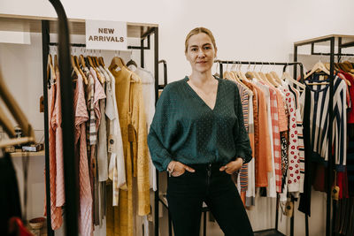 Portrait of smiling female owner standing in clothing store