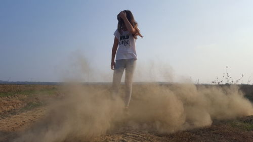 Rear view of woman standing on land against sky