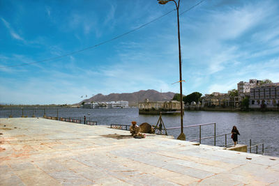 People sitting by lake against sky