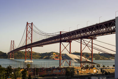 Suspension bridge over river against sky